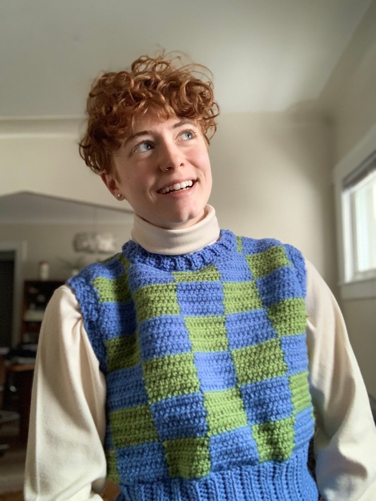 Jess wears a crocheted sweater vest.